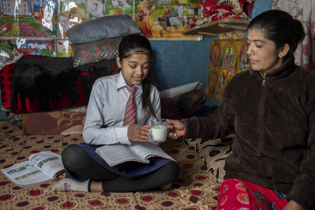 Bishnu Chopai, 34, serves cow milk to her daughter before she leaves for school at her home village Phalebas in Parbat, Nepal. 18 February 2022.