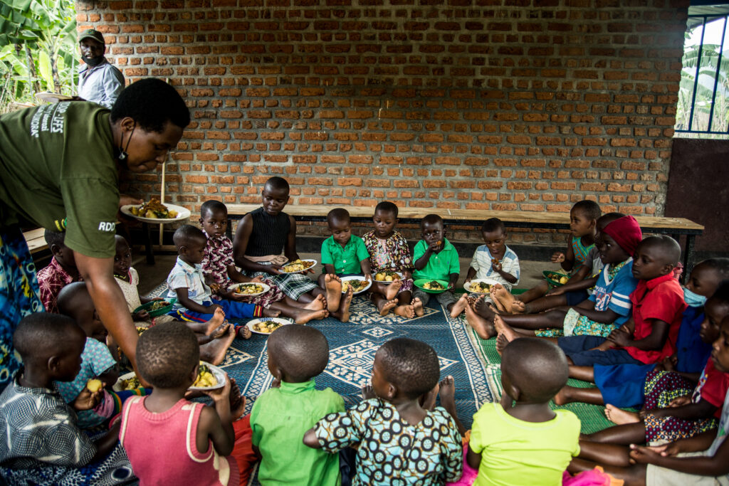 Mothers serving and sharing a nutrition meal and milk with children during a Community Kitchen program supported by a livestock farmer field school group in Rugera sector, Nyabihu district, Northern province of Rwanda.